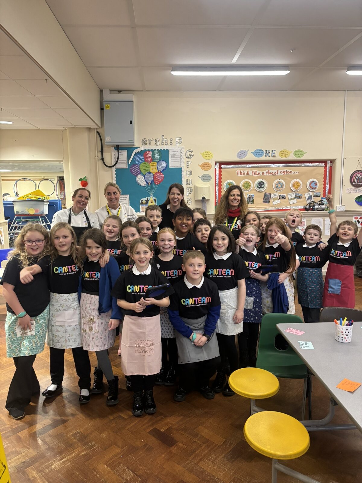 Primary-aged CanTeam Crew members in CanTeam T-shirts and aprons with adult supporters